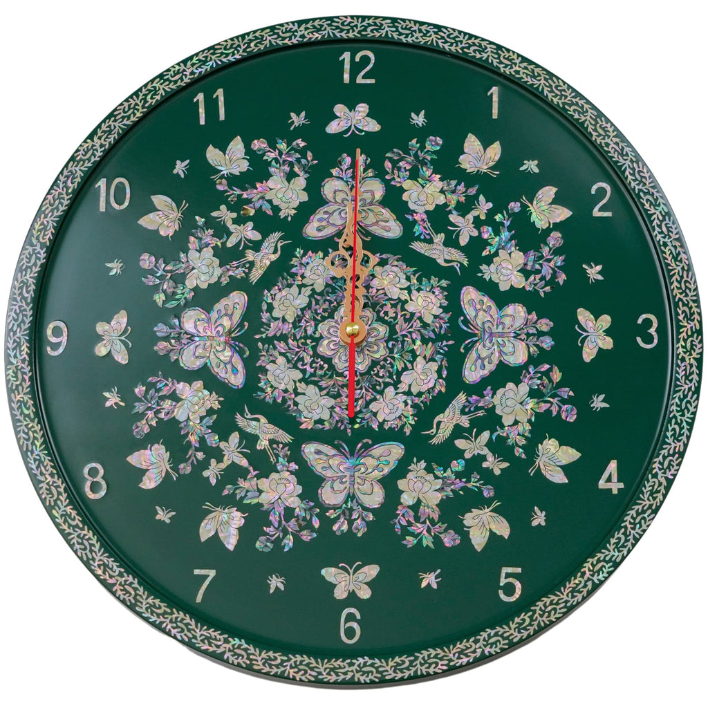 Elegant wall clock with a navy blue background, adorned with a mother of pearl design featuring butterflies and flowers, and gold hands centered over the design. The clock is bordered by a detailed leaf pattern.