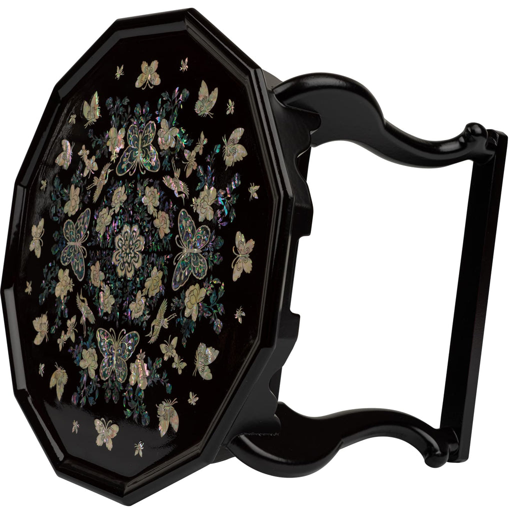 A black lacquer tea table with intricate mother-of-pearl inlay of butterflies and flowers, standing on elegant curved legs.