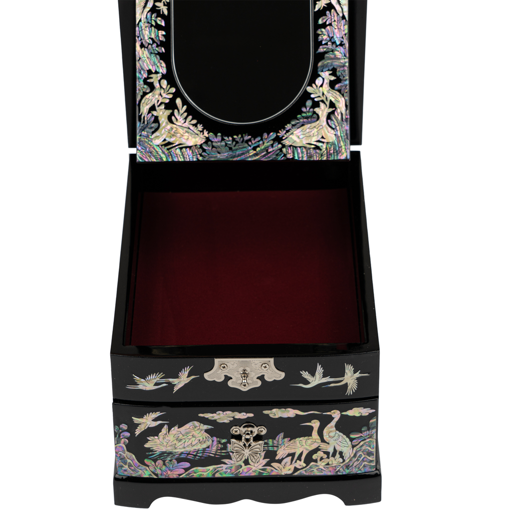 A jewelry box with a mirror in the lid, mother-of-pearl inlay with cranes and plants on the exterior, a silver latch, and a plush red interior for storing jewelry.