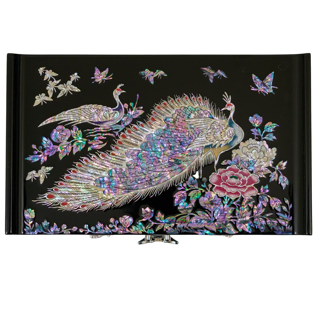 A mother-of-pearl jewelry box with a detailed peacock and rose design on the lid, reflecting iridescent colors, paired with black lacquer and metal clasps.