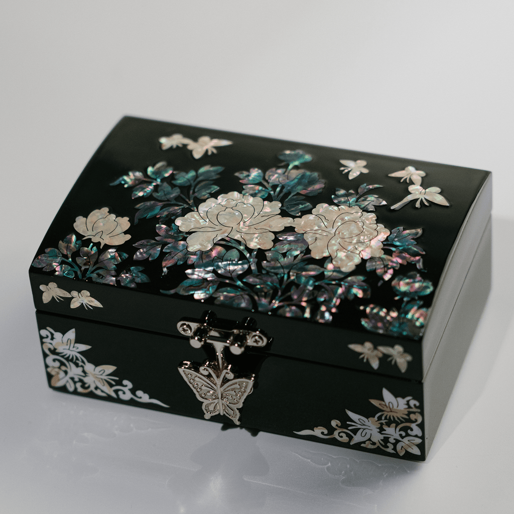  A black jewelry box adorned with iridescent mother-of-pearl inlay showcasing flowers and butterflies, adding a luxurious touch to any decor.