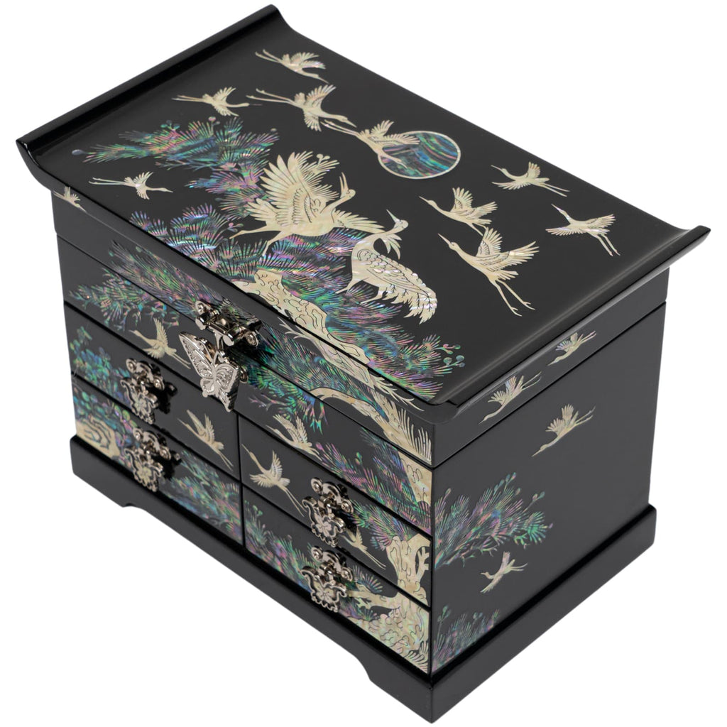The image features an elegant black jewelry box adorned with a mother-of-pearl inlay of cranes and iridescent foliage. The box appears to have multiple drawers, each with ornate metal handles, emphasizing its luxurious and traditional design.