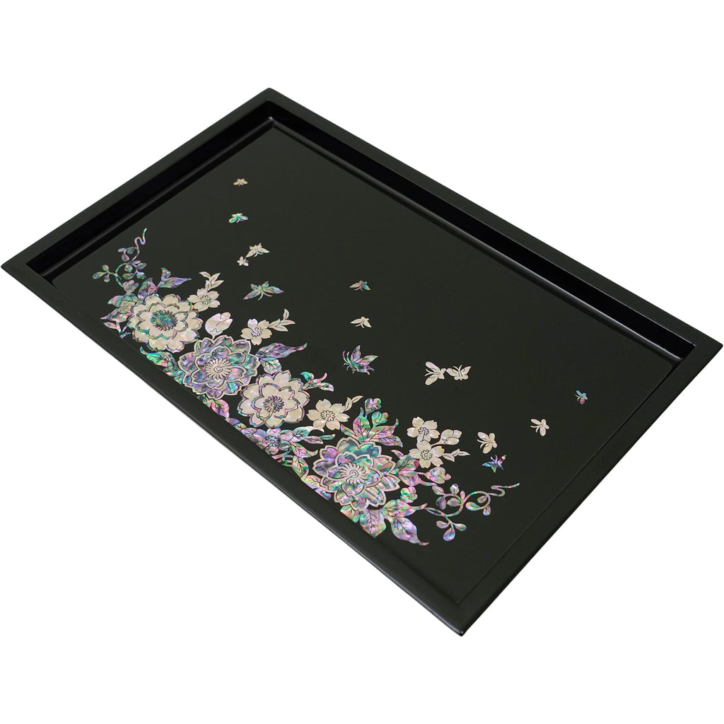 An angled view of a mother-of-pearl inlaid tray with a radiant floral and butterfly design on a deep black background, showcasing the intricate craftsmanship.