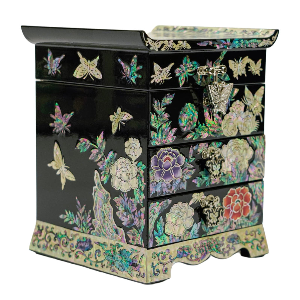 A black, mother-of-pearl inlaid jewelry box with a scalloped base and flowers and butterflies decoration on its left side.