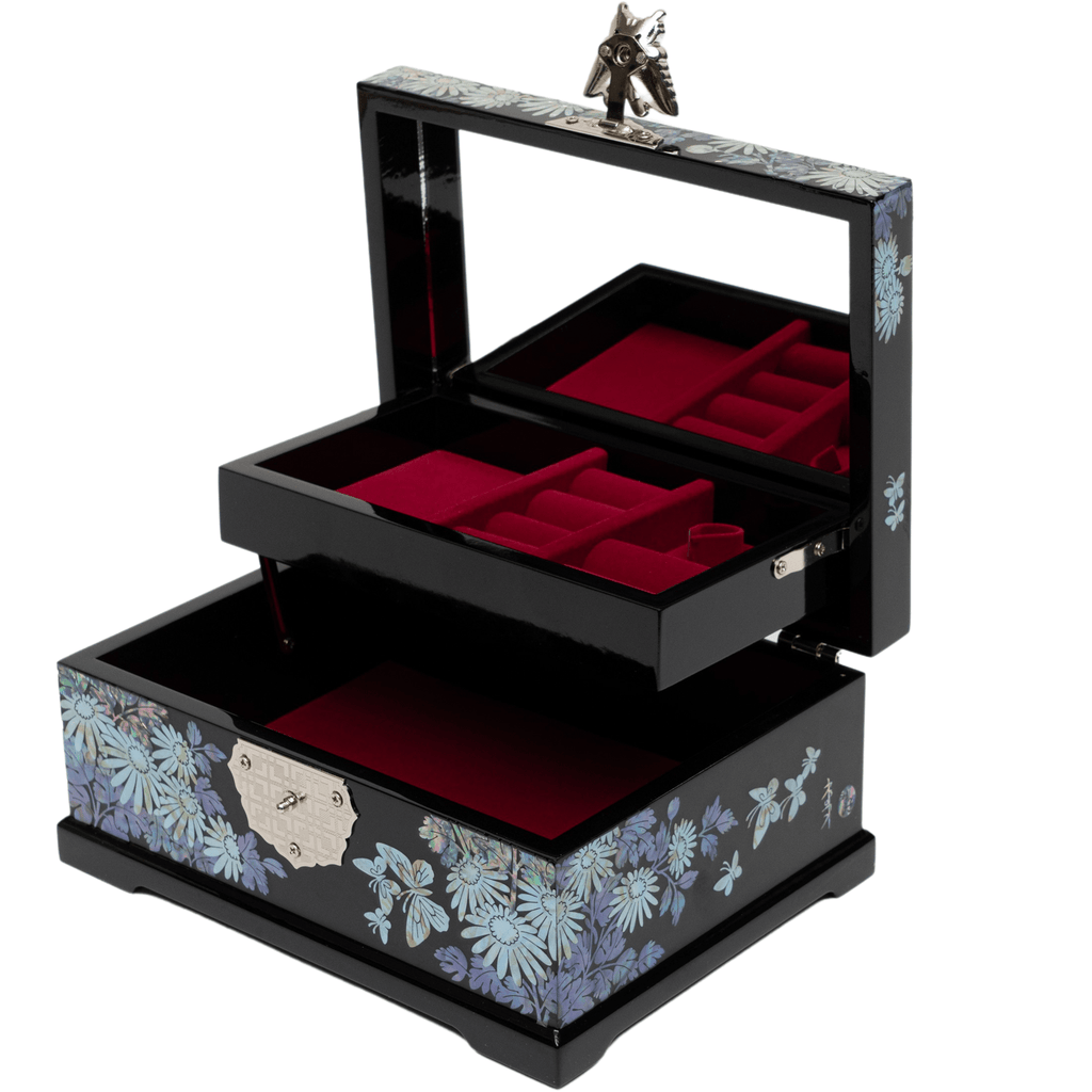 An open black jewelry box with a mother-of-pearl floral design, a mirrored lid with a butterfly clasp, and red velvet-lined trays.