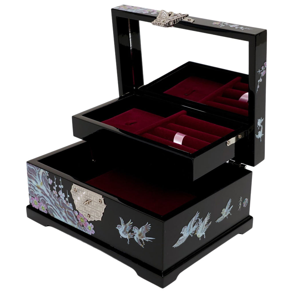 An open, two-tiered black lacquered jewelry box with mother of pearl inlay, featuring bird designs and a plush red interior